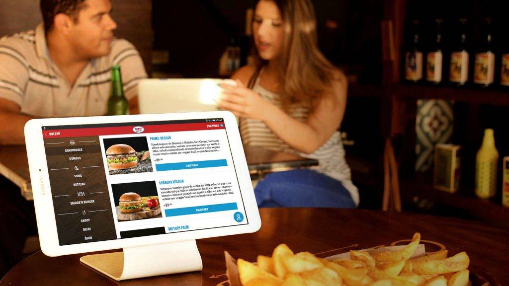 clientes no restaurante com tablet sendo usado para ver o cardápio online
