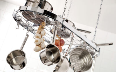 Conjunto de panelas de aço inox pendurado em suporte de teto numa cozinha